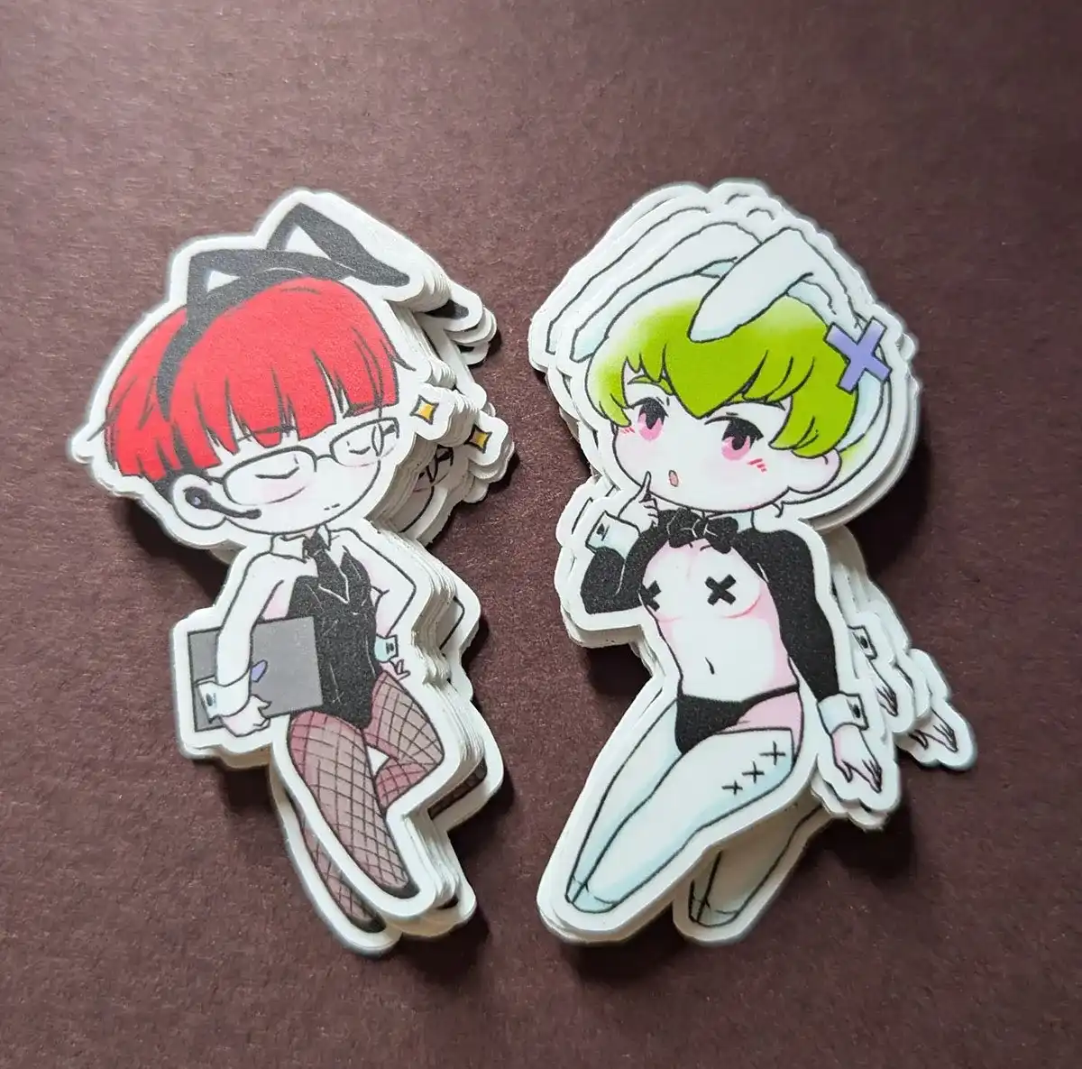 Stickers featuring 2 guys in bunny suits and reverse bunny suits. The one on the left is holding some office equipment like a laptop and smirking, while the other poses cutely with a finger up to his face.